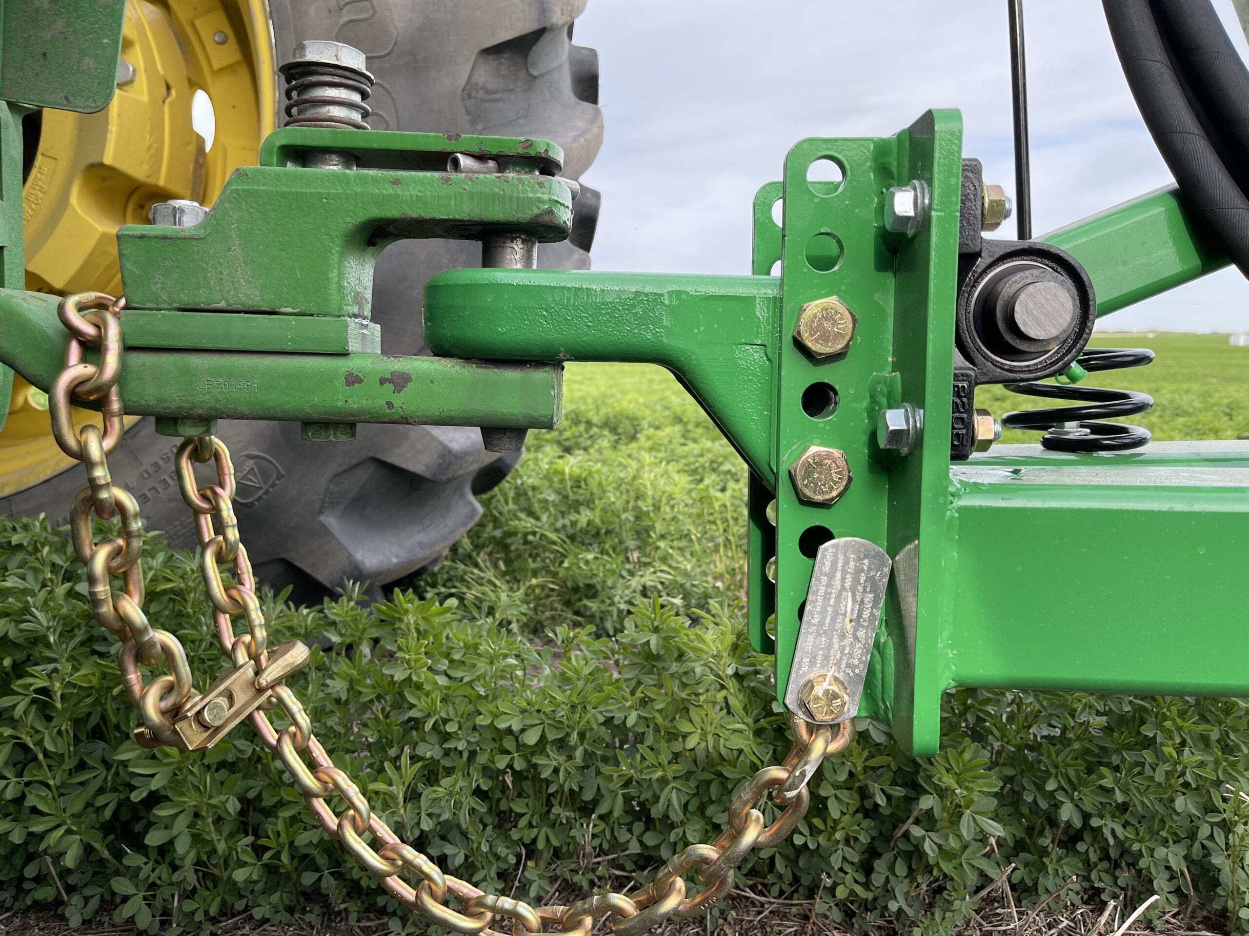 Green tractor hitch assembly with safety chains and spring