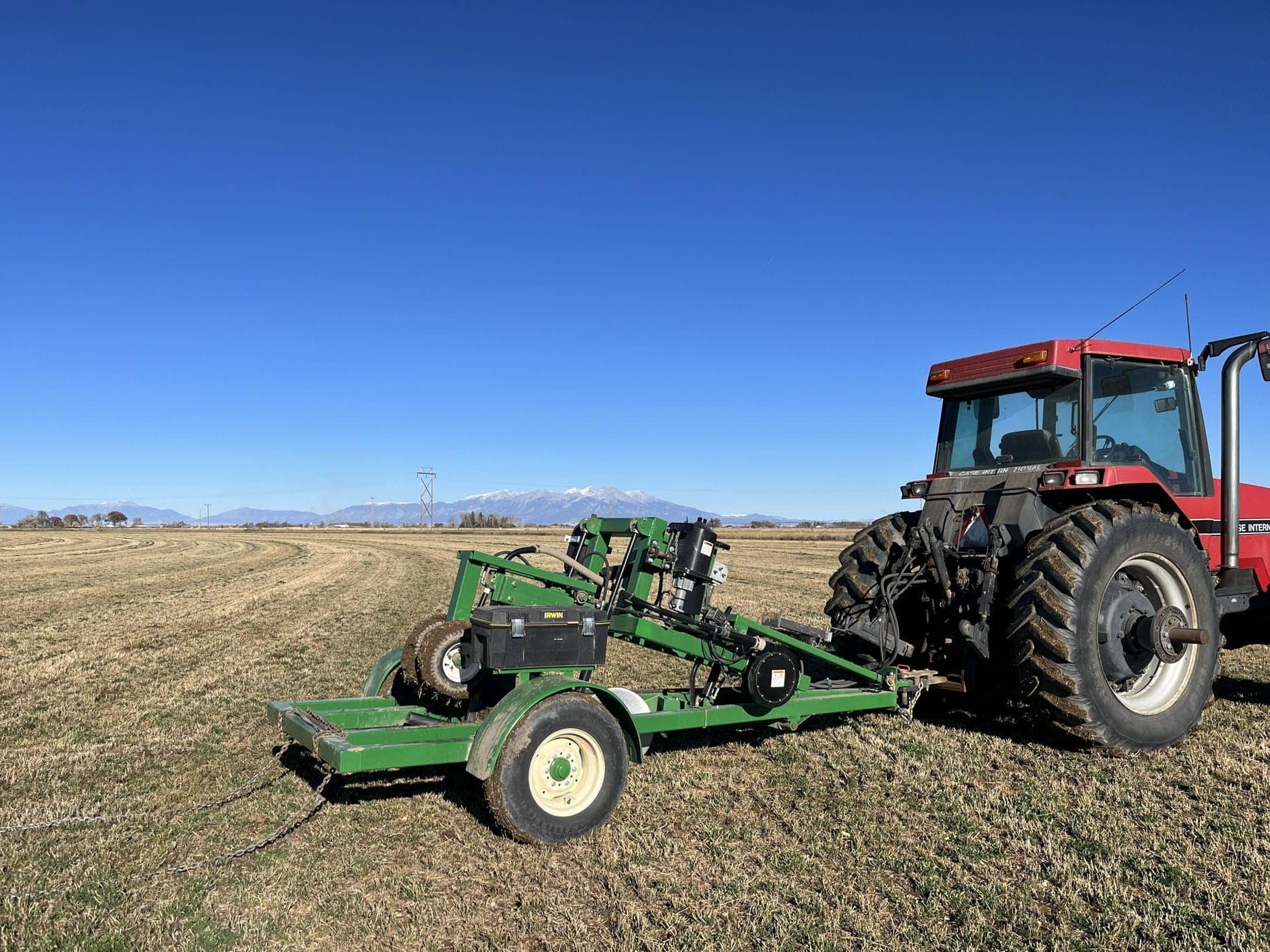 Red tractor with green farm implement in field