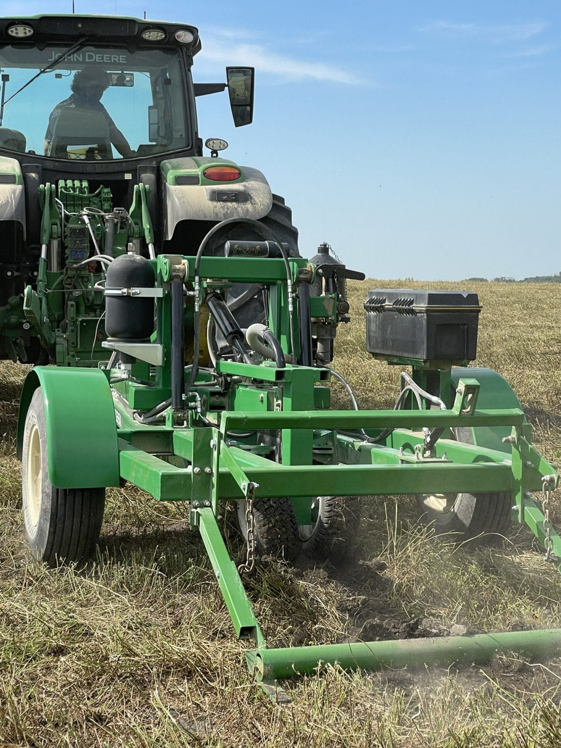 John Deere tractor towing green field cultivation equipment